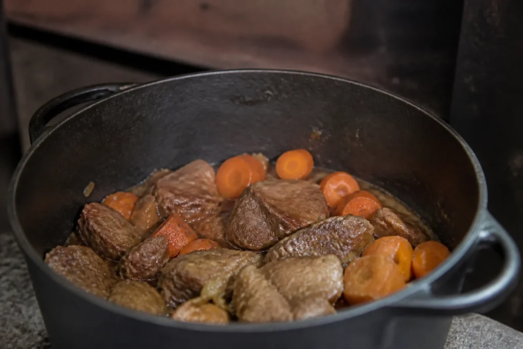 Cocotte en fonte noire remplie de viande et carottes