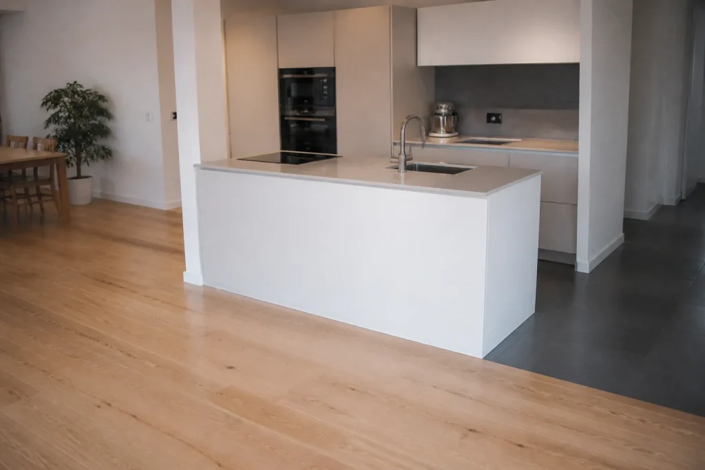 Ilot blanc devant un parquet clair et carrelage gris