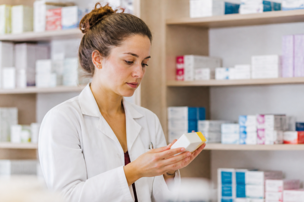 Pharmacienne en blouse blanche tenant une boite de medicaments