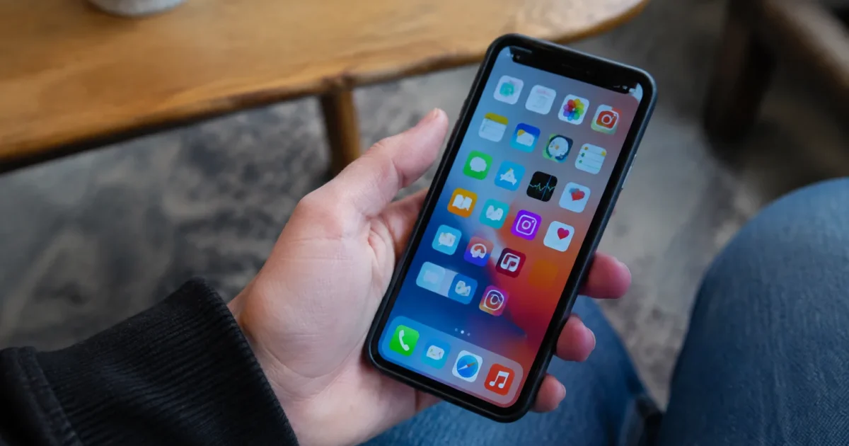 Main tenant un smartphone affichant des icones d'applications colorees