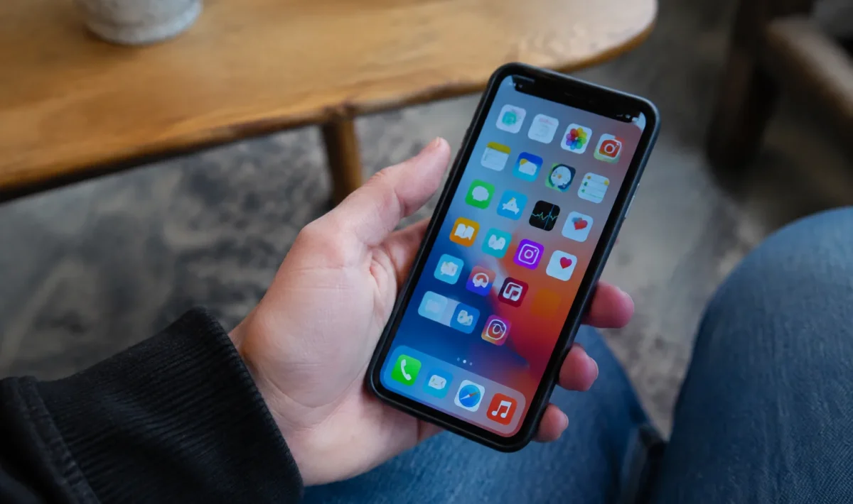 Main tenant un smartphone affichant des icones d'applications colorees